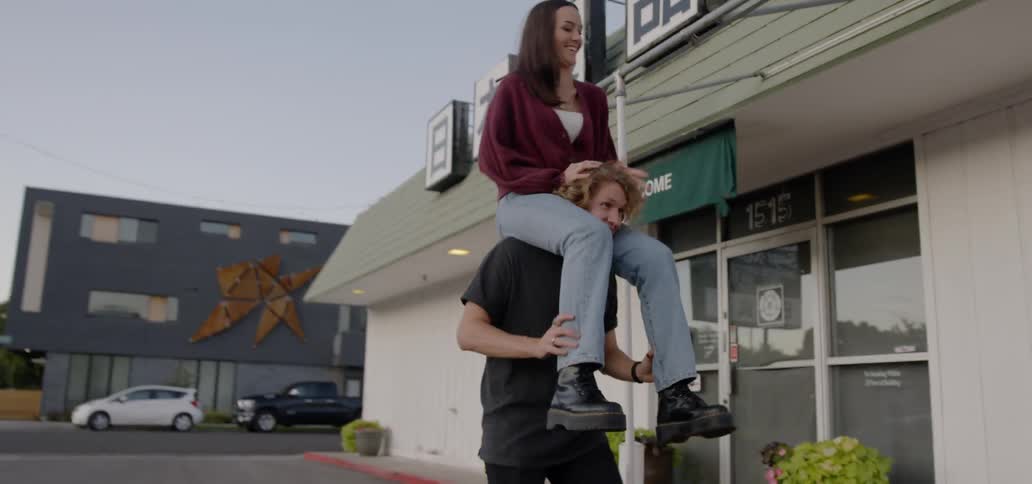 A young man carries a young woman on his shoulders