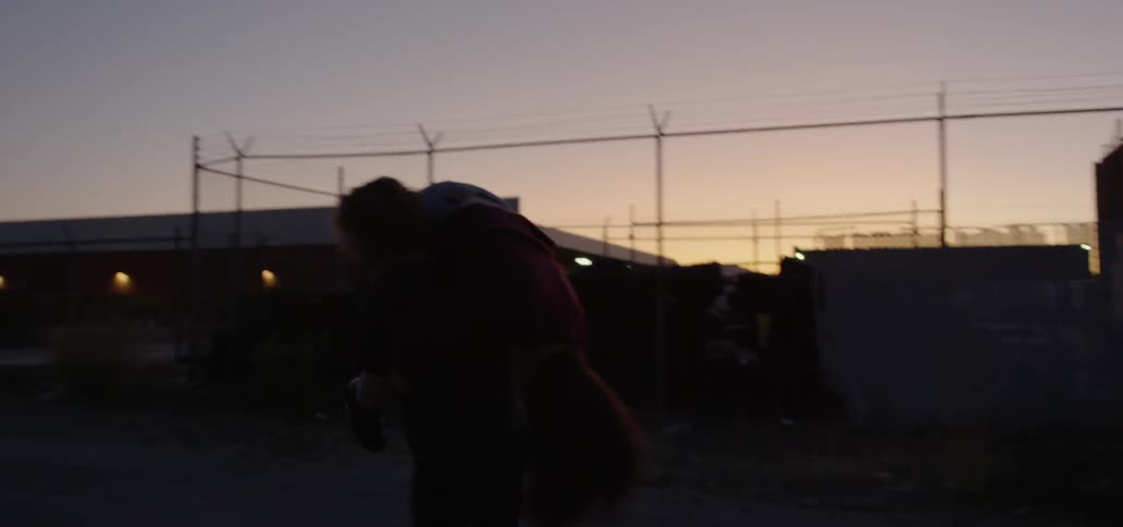 A man playfully carrying a woman over his shoulder at sunset