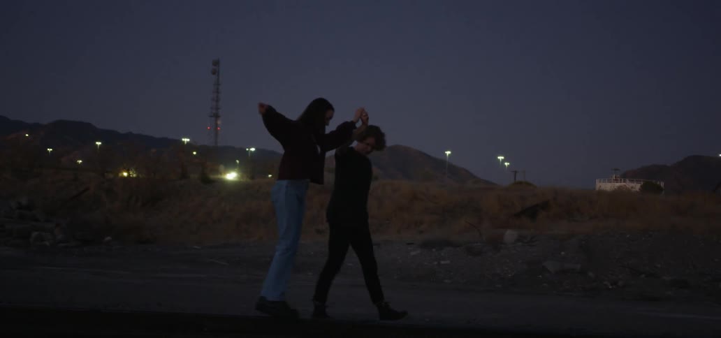 A man and a woman holding hands and walking together at night