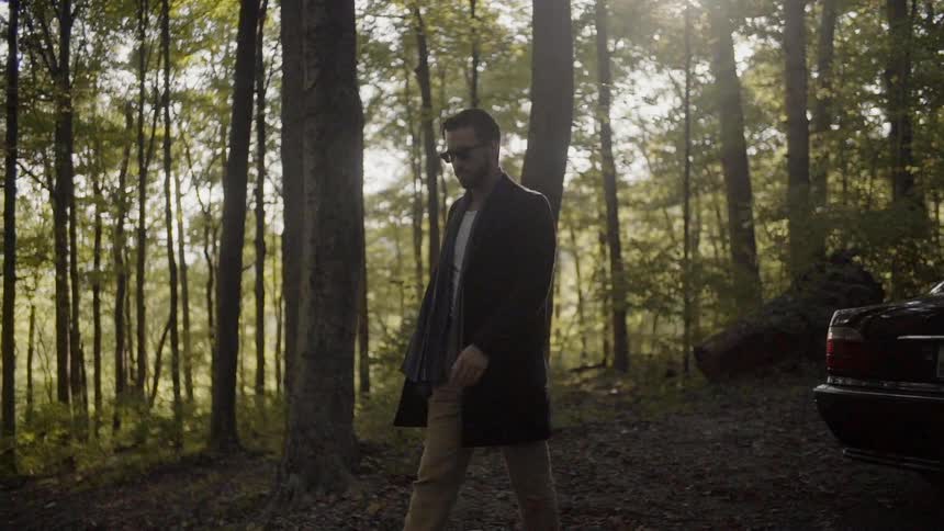 A male wearing sunglasses walking in the woods