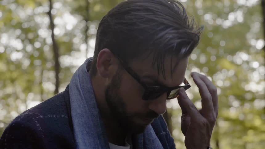 A white man puts on sunglasses and stares into the distance