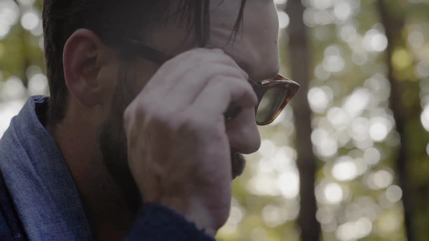 A man puts his sunglasses on in the forest