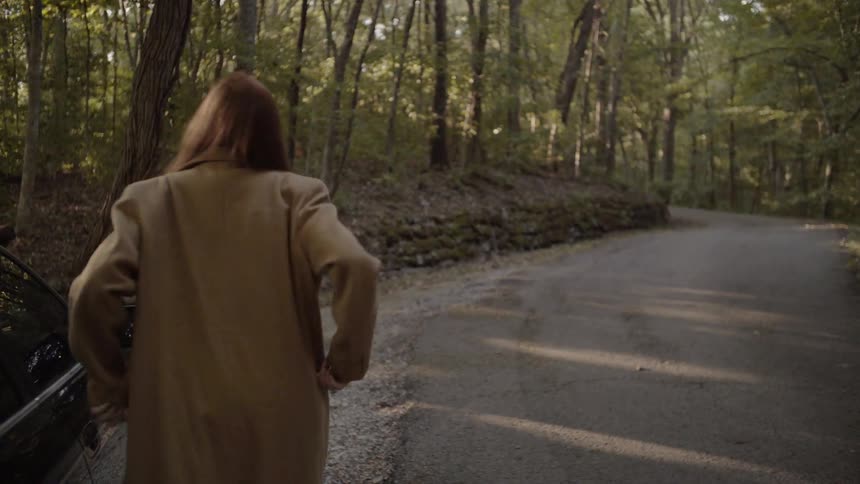 A woman in a coat getting out of a car then walking across the street