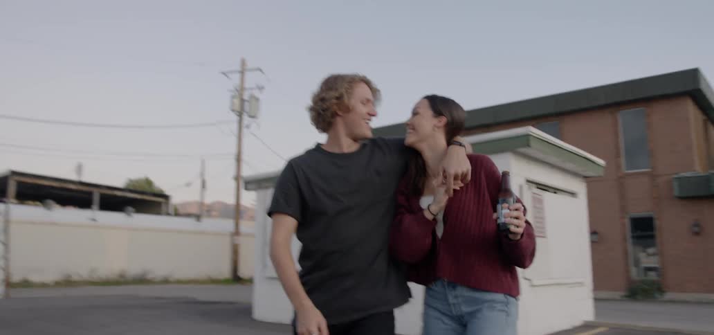 A couple walks across a parking lot holding hands