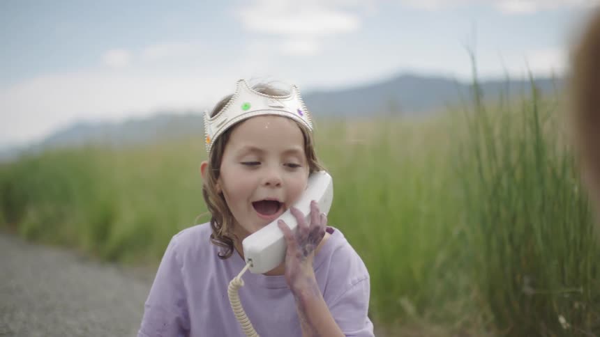 A child pretends to talk on an old phone