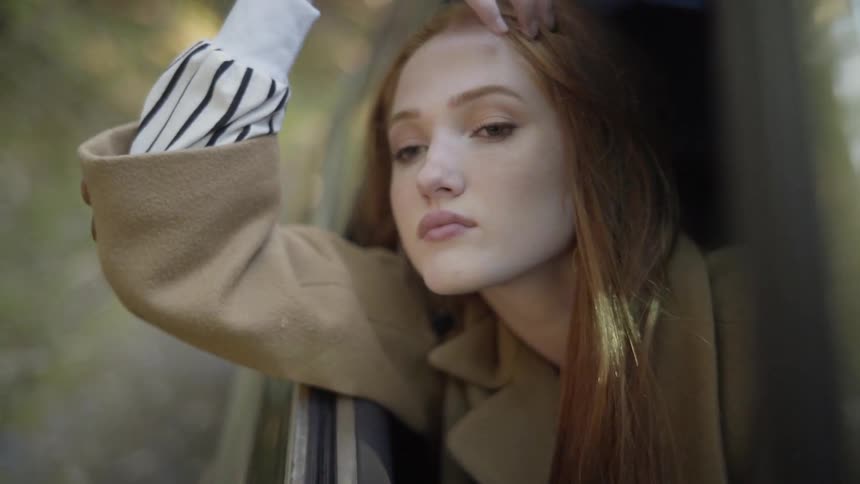 A woman rides in a car with her head and arm out the window