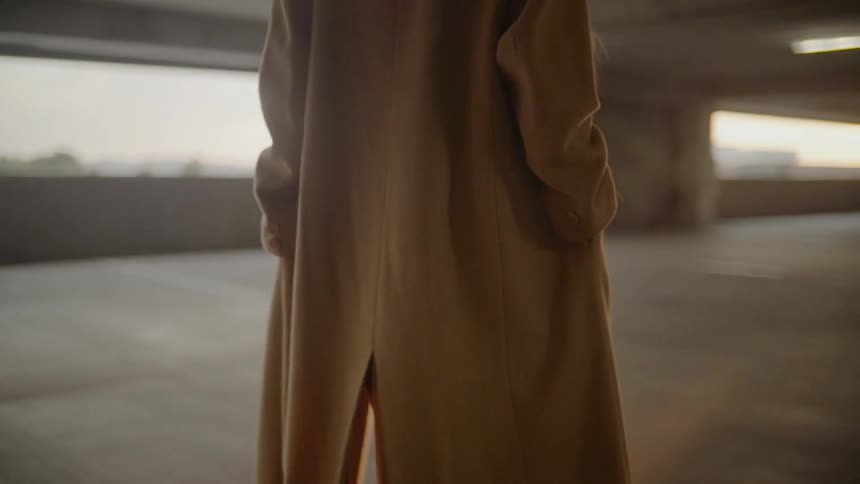 Woman in coat walks past man in coat in parking structure