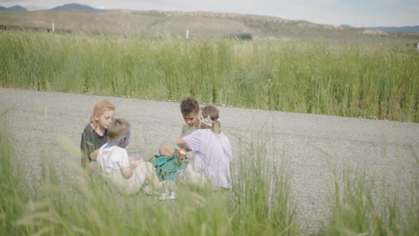 Children sit on the field talking and playing