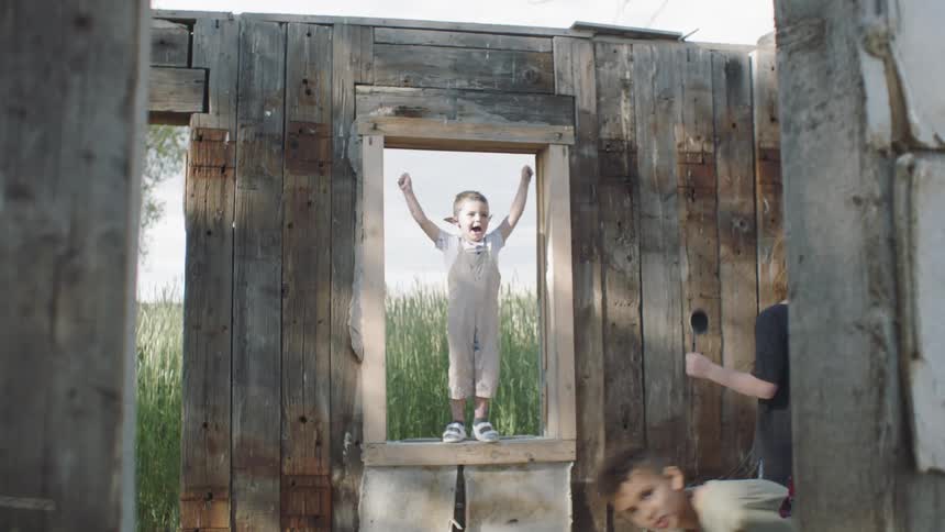 A boy standing on a windowsill in an old abandoned house