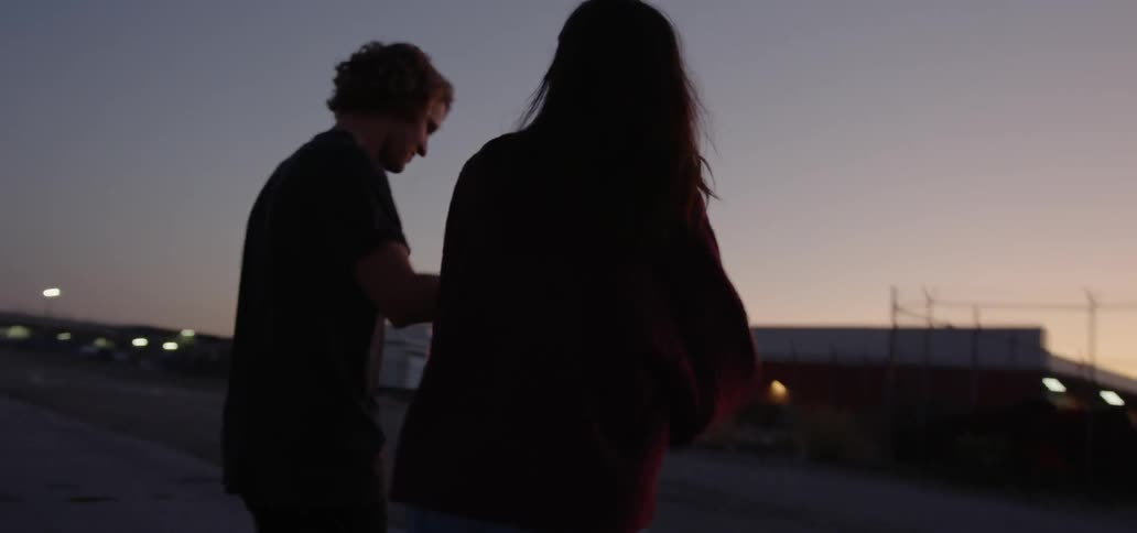 Couple walk together holding hands and hugging at dusk
