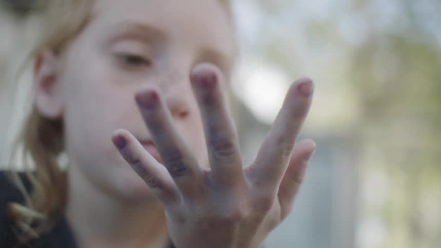 A child stares at a bug crawling on her hand
