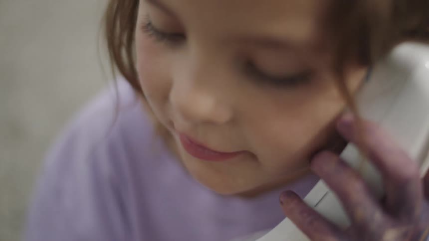 A child eating an apple while playing with an old phone