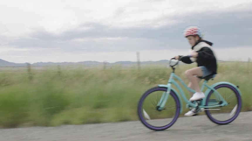 A girl rides a bike on the side of the road