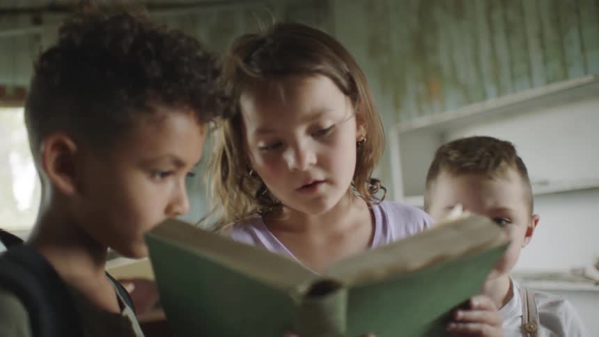 A small child reads a book to another child