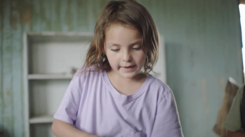 Girl dusts off book in abandoned cluttered home