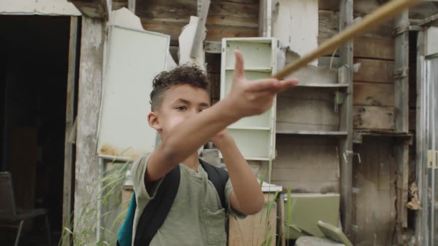 A child blows into a tube in a dilapidated house