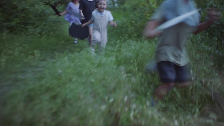 A group of young kids in costumes running through the woods
