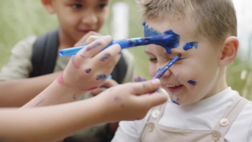 Children put blue paint on a boys face