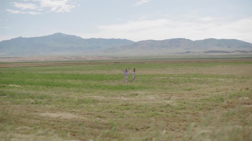 Children play in field next to mountains