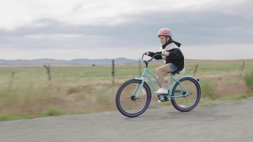 A child rides a bike down a country road