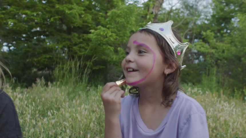 A little girl puts lipstick all over her face
