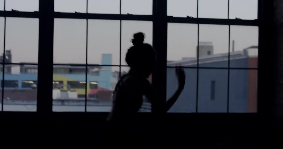 Silhouette of a dancer in a building in the dark near a window
