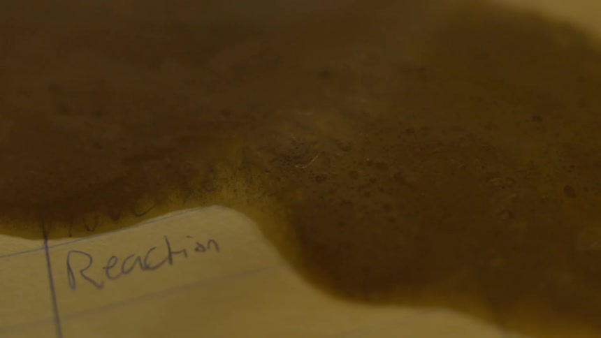 Dark liquid is spilled on a piece of paper with notes