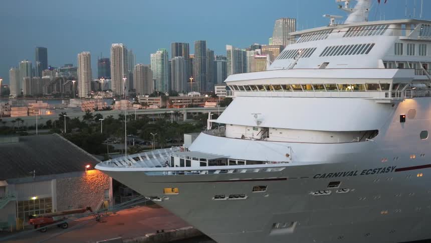 A large yacht is docked by a city at sunset