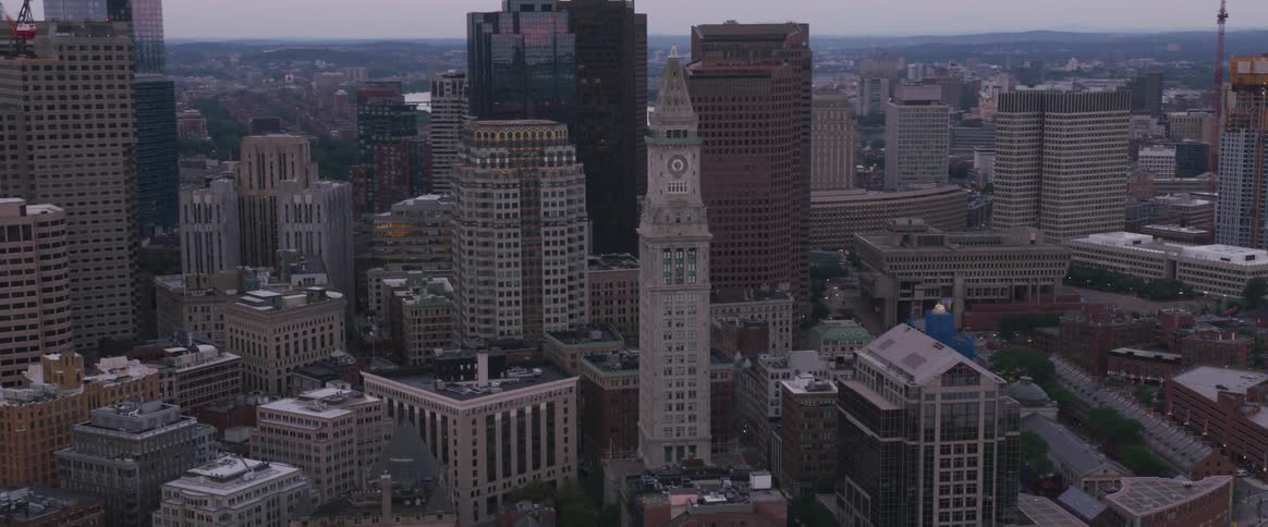 A clock tower stands among skyscrapers in a city