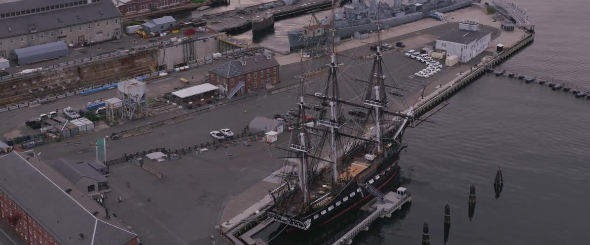 A three mast ship in a harbor during the day