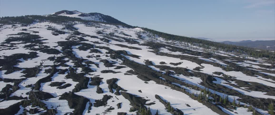 The camera flies over snow on a mountain side