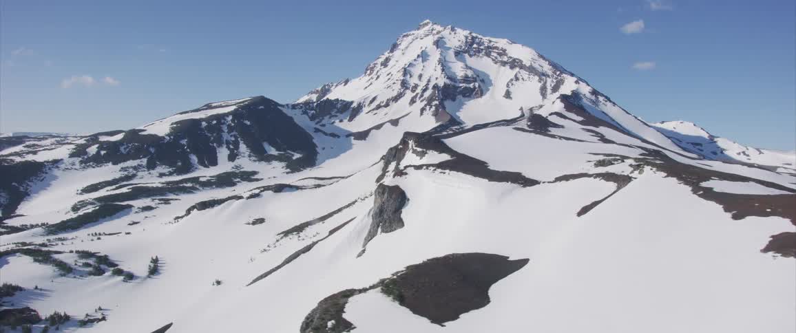 A mountain looms over the surround snow covered terrain