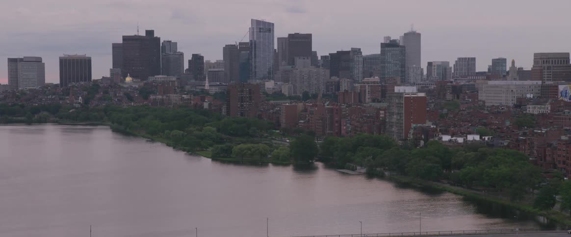 Traffic drives across a bridge across a river next to a city