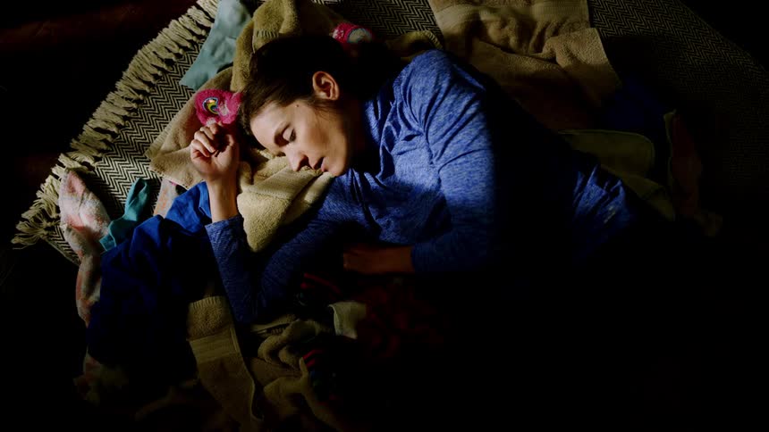 Woman asleep on rug on floor with blankets