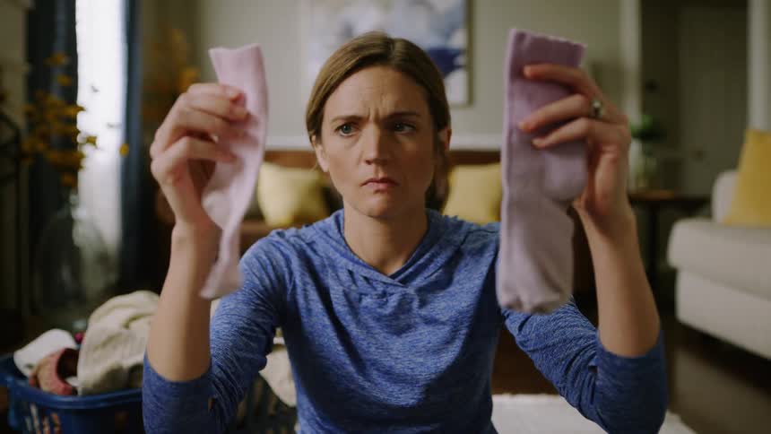 Woman doing laundry compares two pink kid's socks trying to find a match.
