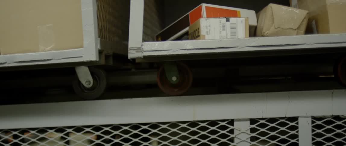 Open wheeled carts carrying packages and boxes to be shipped move along on a platform