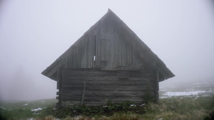 A wooden cabin at wintertime with fog in the background