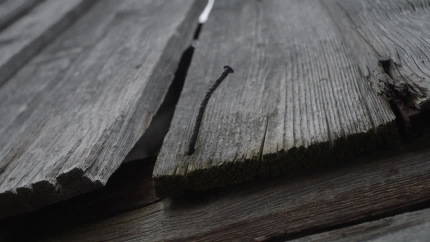 The nail is hanging out of the wooden board