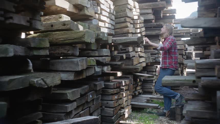 A man is shopping through stacks of wood