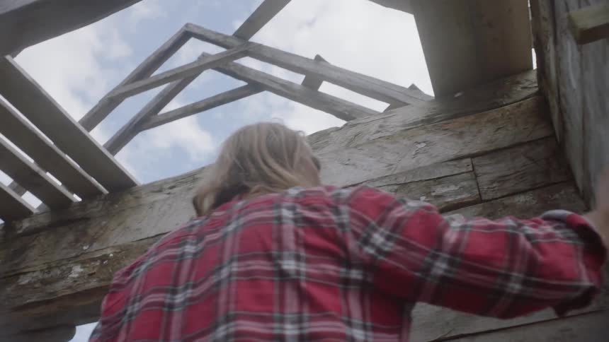 A man is searching around a wooden structure