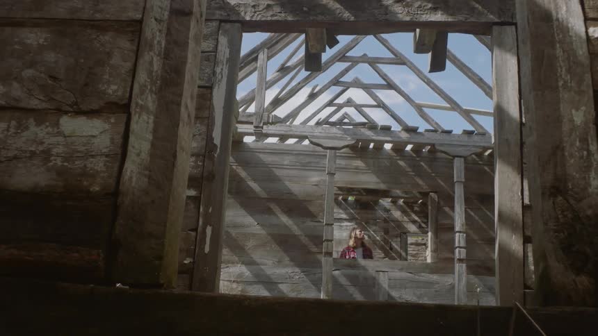 A man is walking through the frame of a wooden house