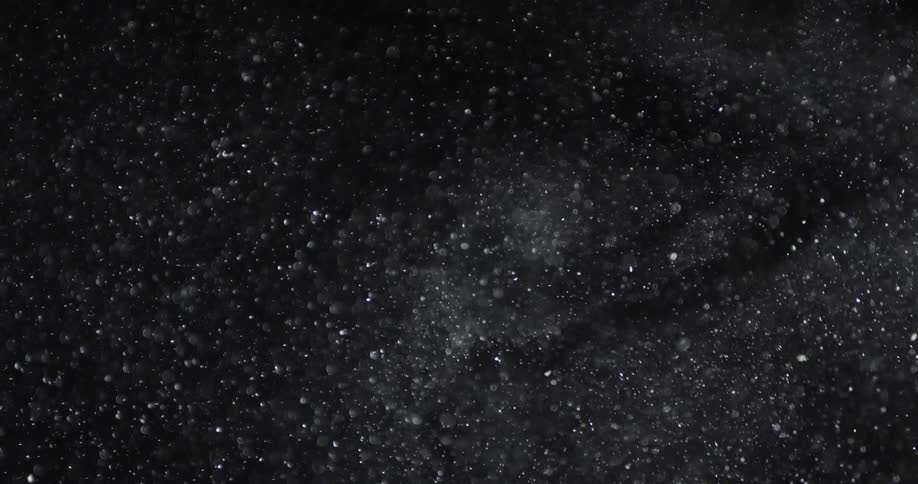 Abstract floating particles swirling in front of a black background