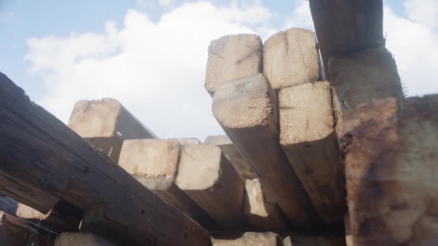 The camera looks at a stack of lumber