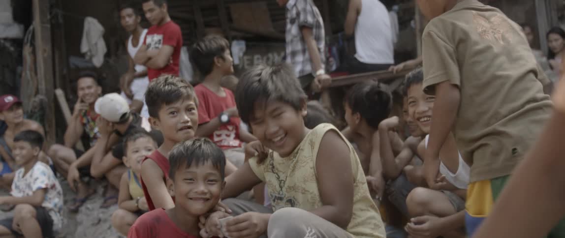Group of children in third world village sitting together smiling