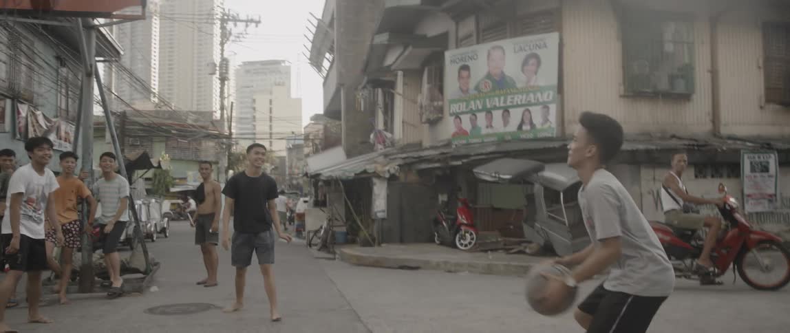 A group of children play basketball in the street