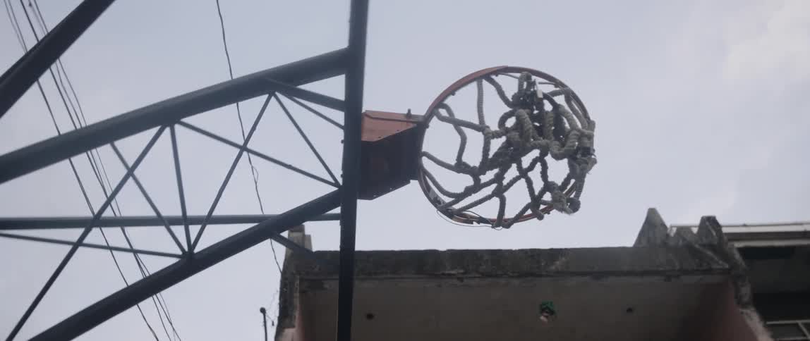 A view looking up at the bottom of a basketball hoop on a cloudy day