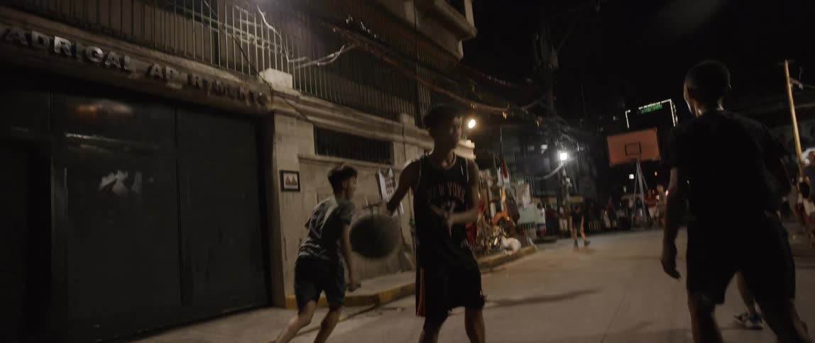 Teenagers play street basket in the suburban area at night