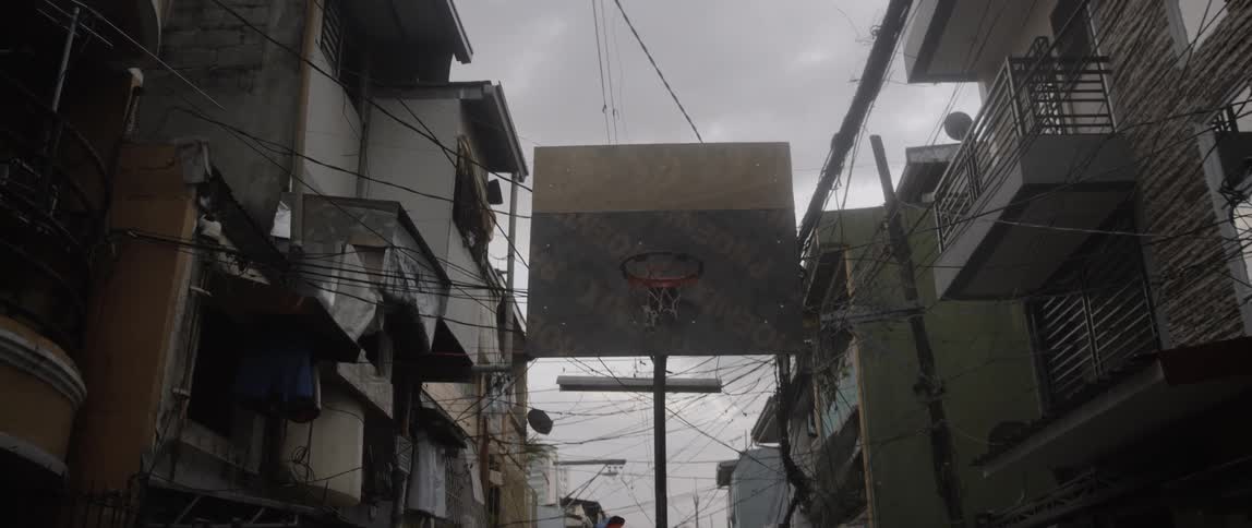 Basketball hoop in center of street between apartment buildings