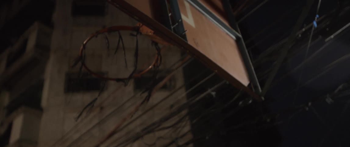 The wind is blowing the string on the basketball hoop at night