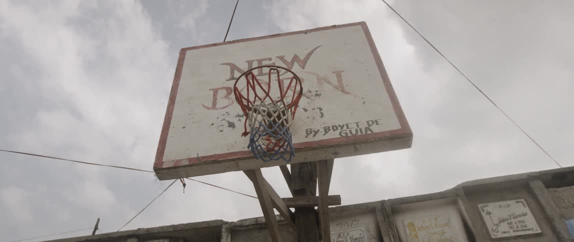 A red white and blue net hangs on an outdoor hoop with a wooden backboard